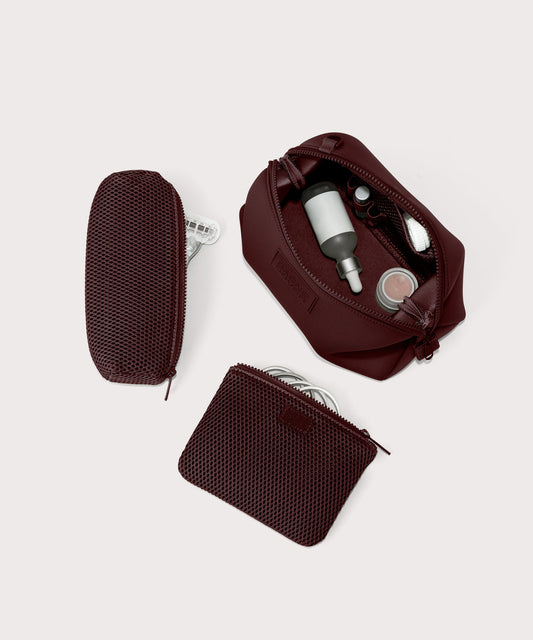 Dagne Dover Large Hunter Toiletry Bag in a deep brown with purple undertones unzipped and seen from above with the removable air mesh pouch alongside it.