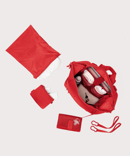 Dagne Dover Large Indi Diaper Backpack in a fiery, saturated red leaning toward orange unzipped showing it's water resistant bag, interior pockets, and changing mat.