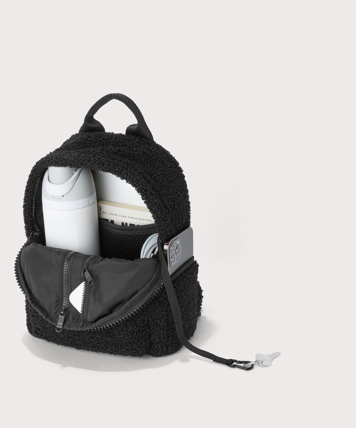 Dakota Small backpack pack in a black. unzipped, top down view. In a Faux Shearling a soft, wool-like plush made with recycled materials