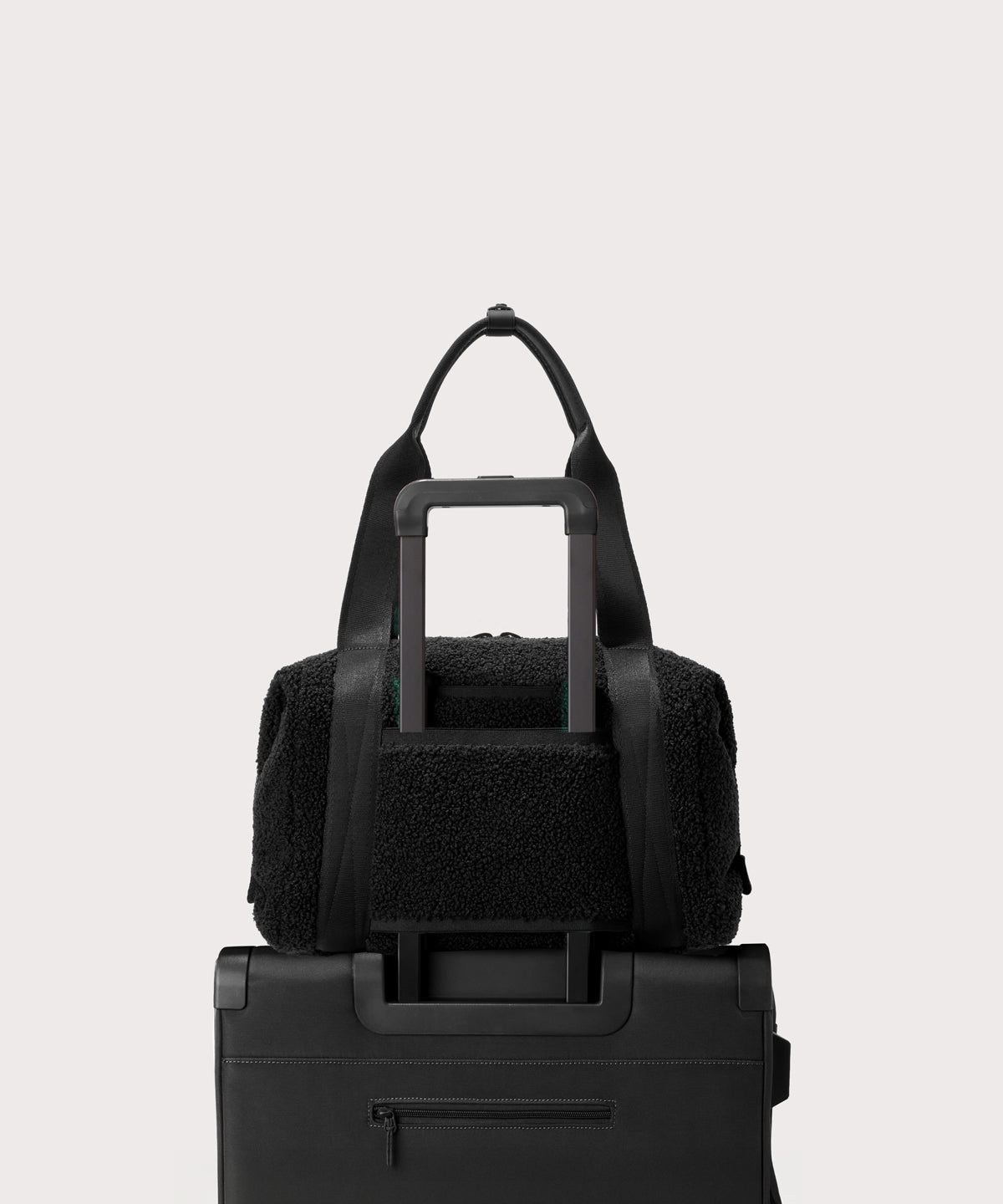 Medium landon carryall in a black.. displaying luggage sleeve. In a Faux Shearling a soft, wool-like plush made with recycled materials.