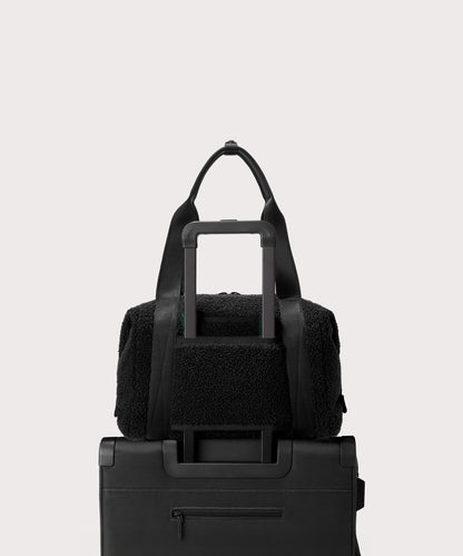 Medium landon carryall in a black.. displaying luggage sleeve. In a Faux Shearling a soft, wool-like plush made with recycled materials.