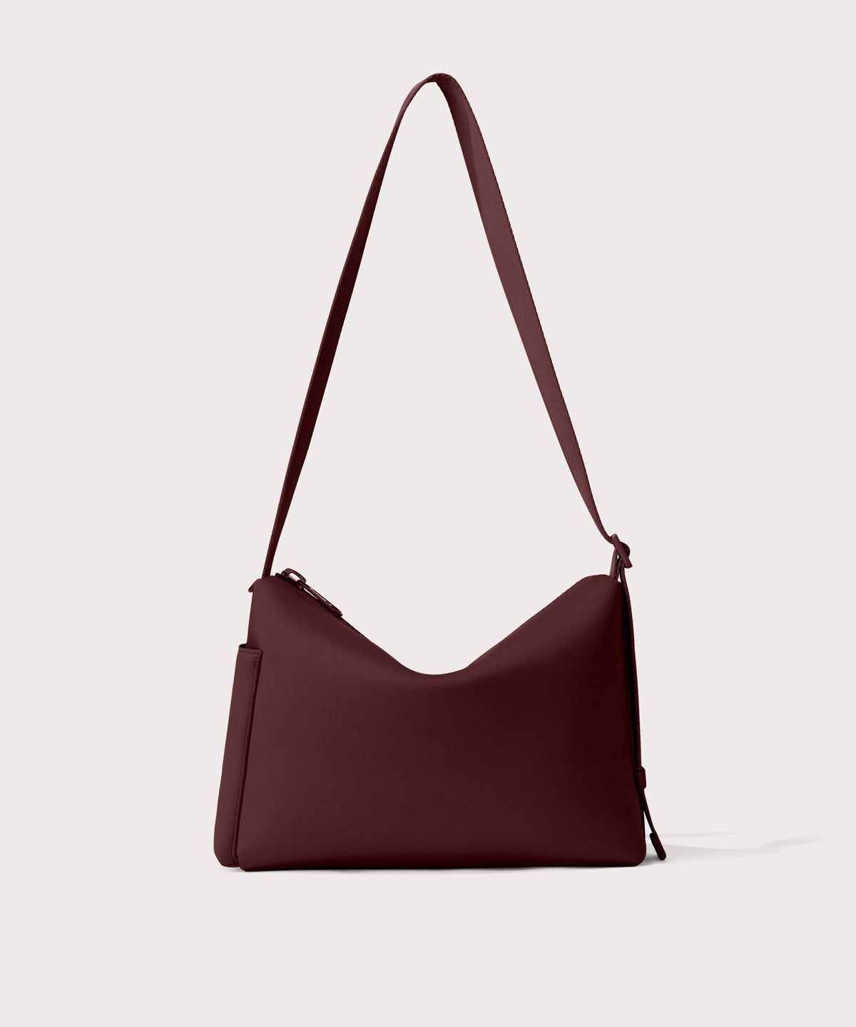 Shoulder bag in a fiery, deep brown with purple undertones reminiscent of maroon seen from the back view showing phone pocket.