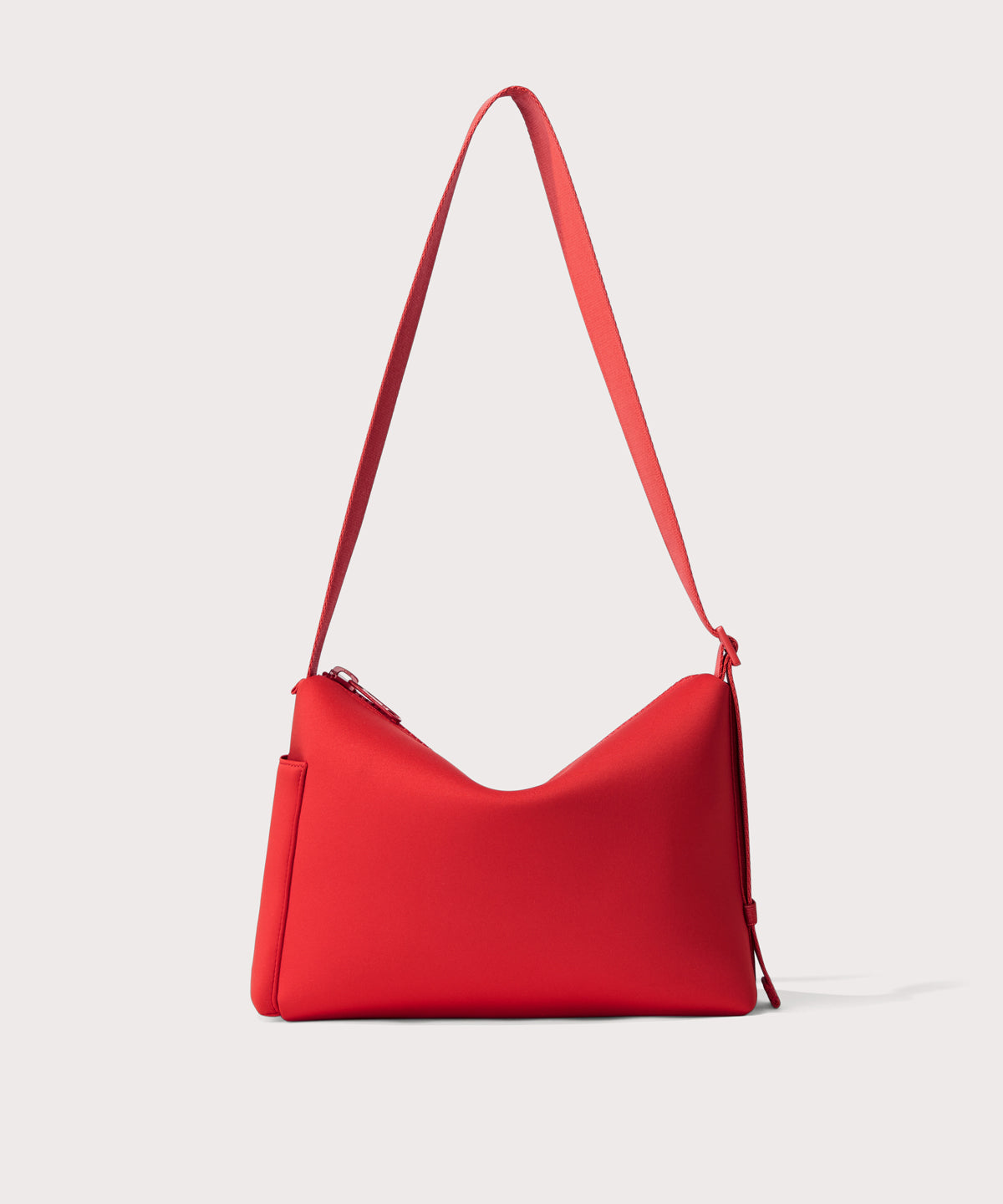 Shoulder bag in a fiery, saturated red leaning toward orange seen from the back view showing phone pocket.
