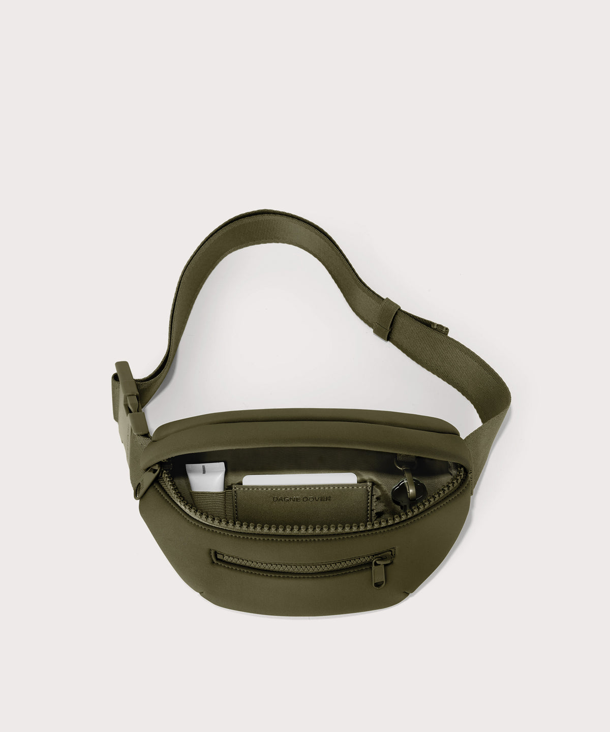 Dagne Dover Ace Fanny Pack in dark green unzipped, exposing the interior pockets