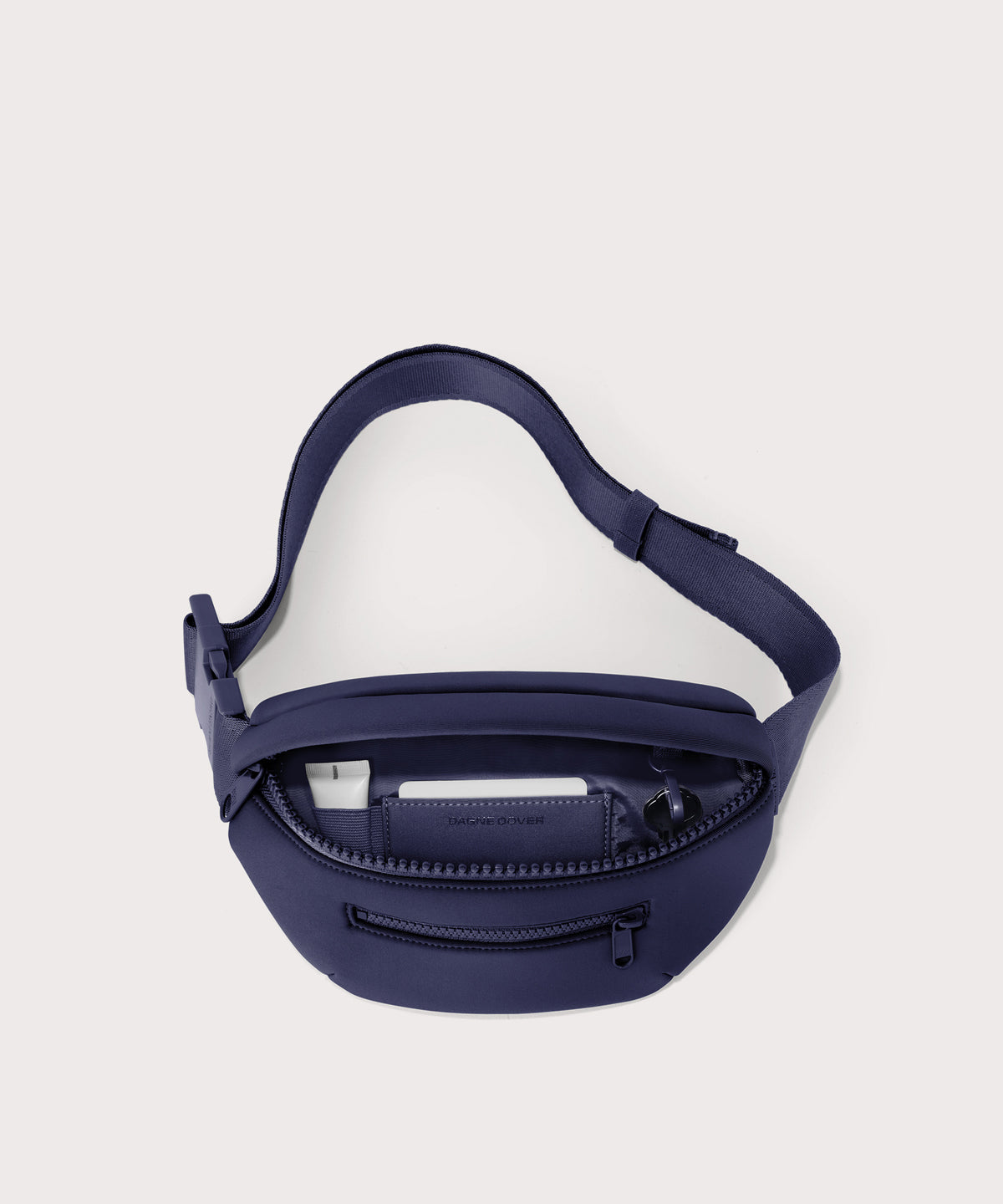 Dagne Dover Ace Fanny Pack in dark blue unzipped, exposing the interior pockets
