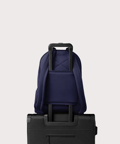 Dagne Dover large Dakota Neoprene Backpack in dark blue strapped to luggage with the neoprene luggage-handle sleeve.