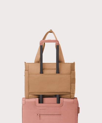 Dagne Dover large Wade Diaper Tote in camel brown with the neoprene luggage sleeve attached to a suitcase handle.