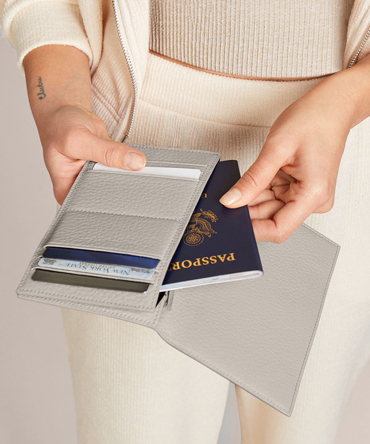 Someone taking their passport out of the Accordion Travel Wallet in white.