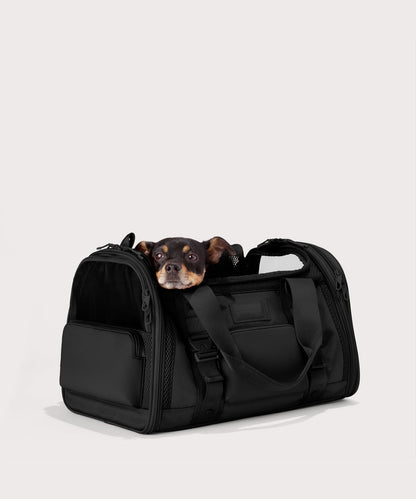 Dagne Dover Large Kyoto Pet Carrier in black seen from an angle with a dog inside the carrier. Caption: Ocho is a 16-lb Chihuahua mix