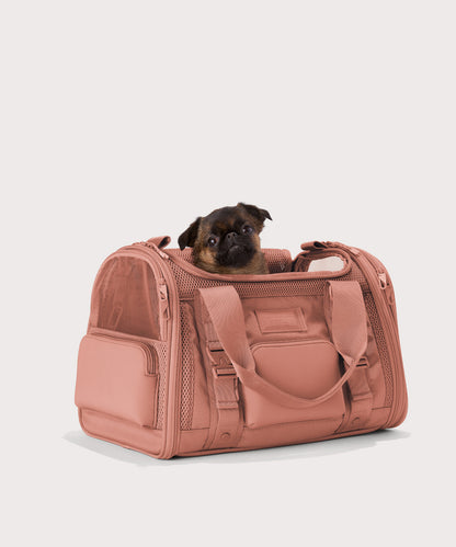 Dagne Dover small Kyoto Pet Carrier in a warm dust pink seen from an angle with a dog inside the carrier. Caption: Ocho is a 16-lb Chihuahua mix