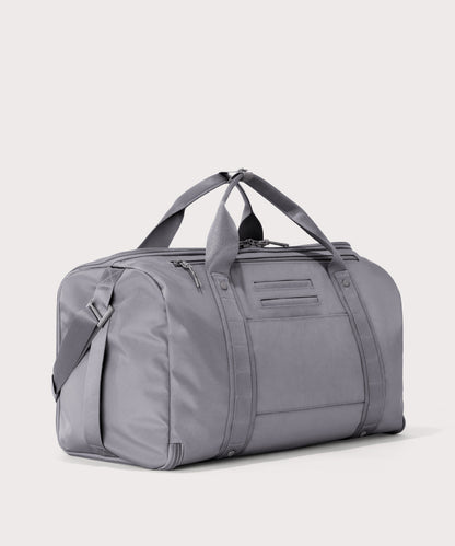 3/4 back view of Monaco garment duffle in a light grey showing back zippered tech pocket and phone/passport pockets