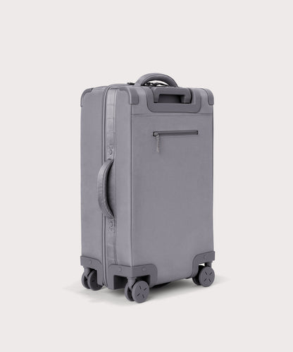 3/4 back view of Seattle carry-on rolling luggage 23.5” in light grey showing side handle and back zippered phone/passport pocket