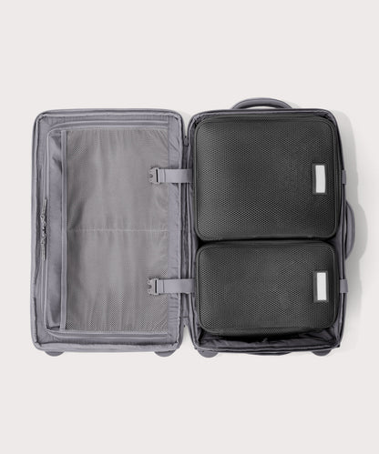 Top down of Seattle carry-on rolling luggage 23.5” in light grey with interior divider zipped and packing cubes packed into the right side.