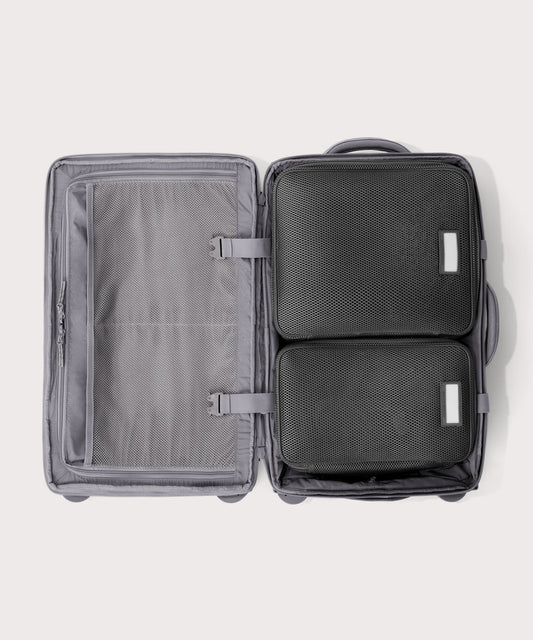 Top down of Seattle carry-on rolling luggage 23.5” in light grey with interior divider zipped and packing cubes packed into the right side.