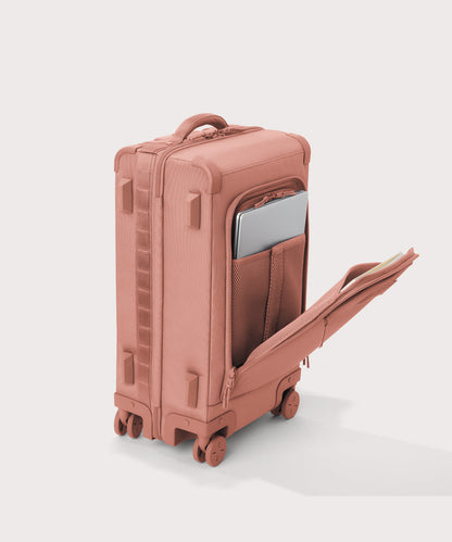 ¾ front view of Seattle carry-on rolling luggage 23.5” in warm dust pink with front flap opened. Caption: Interior slip pocket fits most 16" laptops