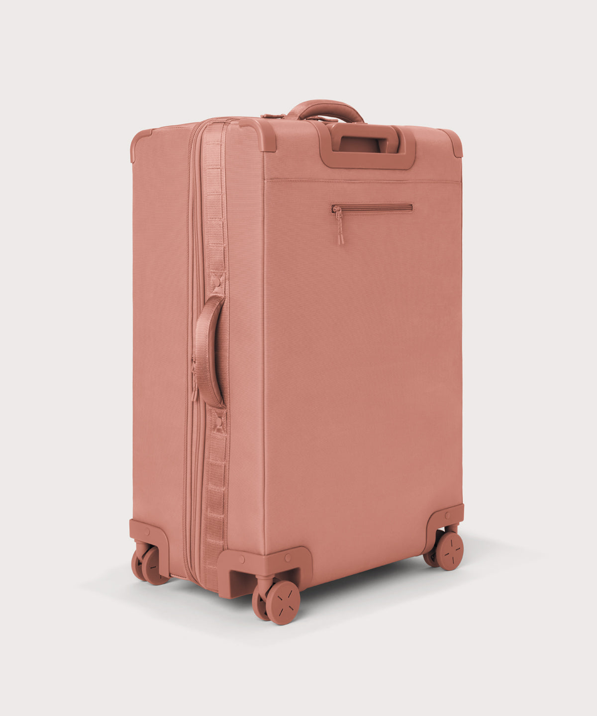 3/4 back view of Sydney checked rolling luggage 28.5” in warm dust pink showing side handle and back zippered phone/passport pocket