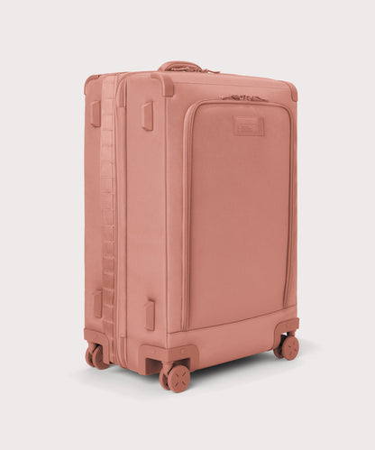 3/4 front view of Sydney checked rolling luggage 28.5” in warm dust pink showing side luggage feet